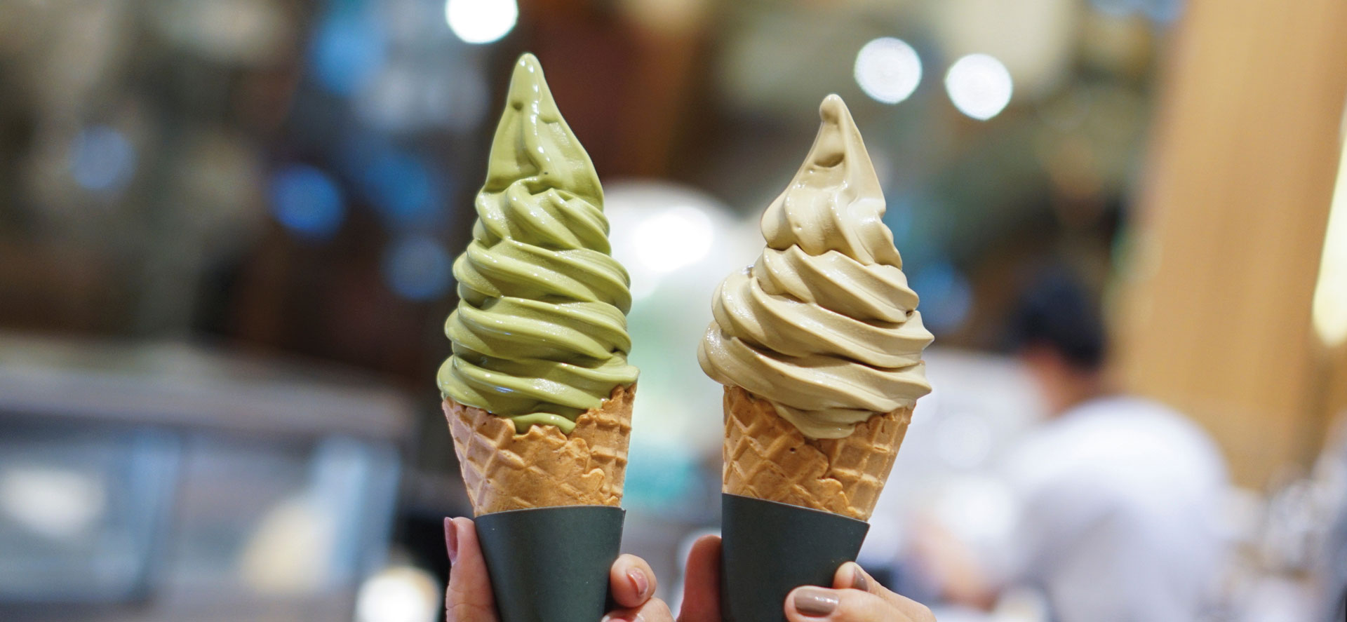 Two soft-serve ice cream cones being held